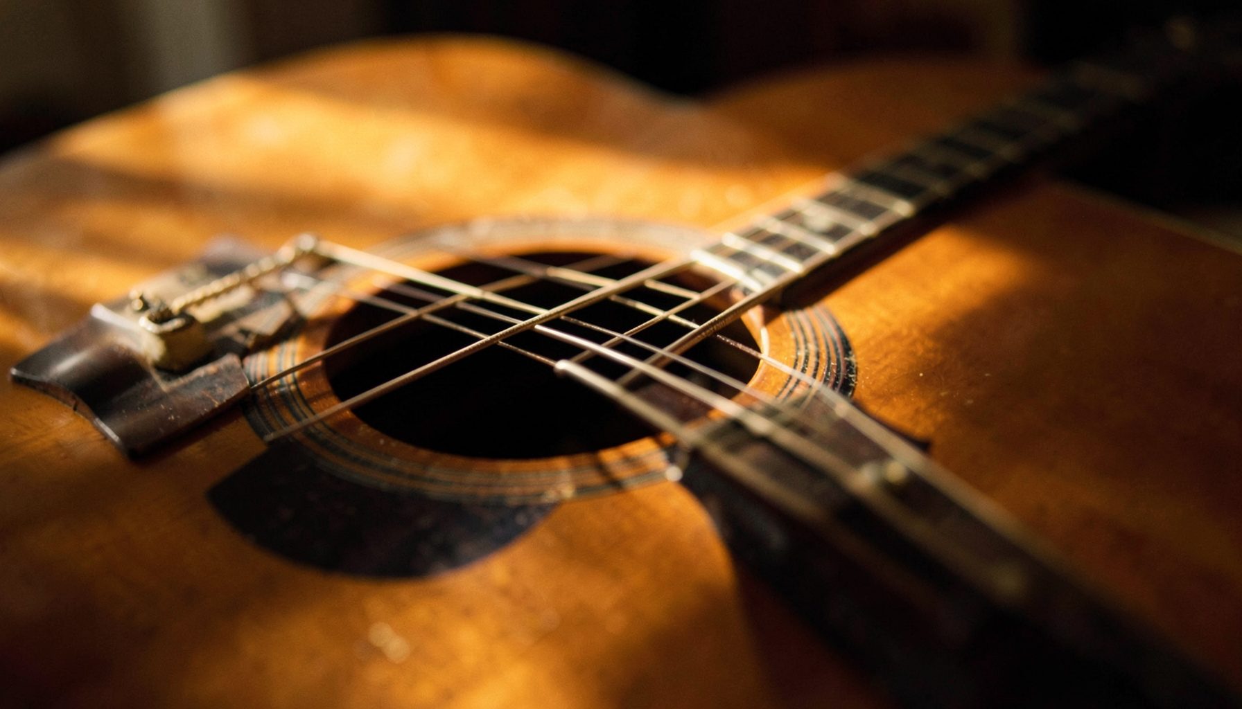 Close-up of an acoustic guitar body and strings, warm golden lighting, calm mood